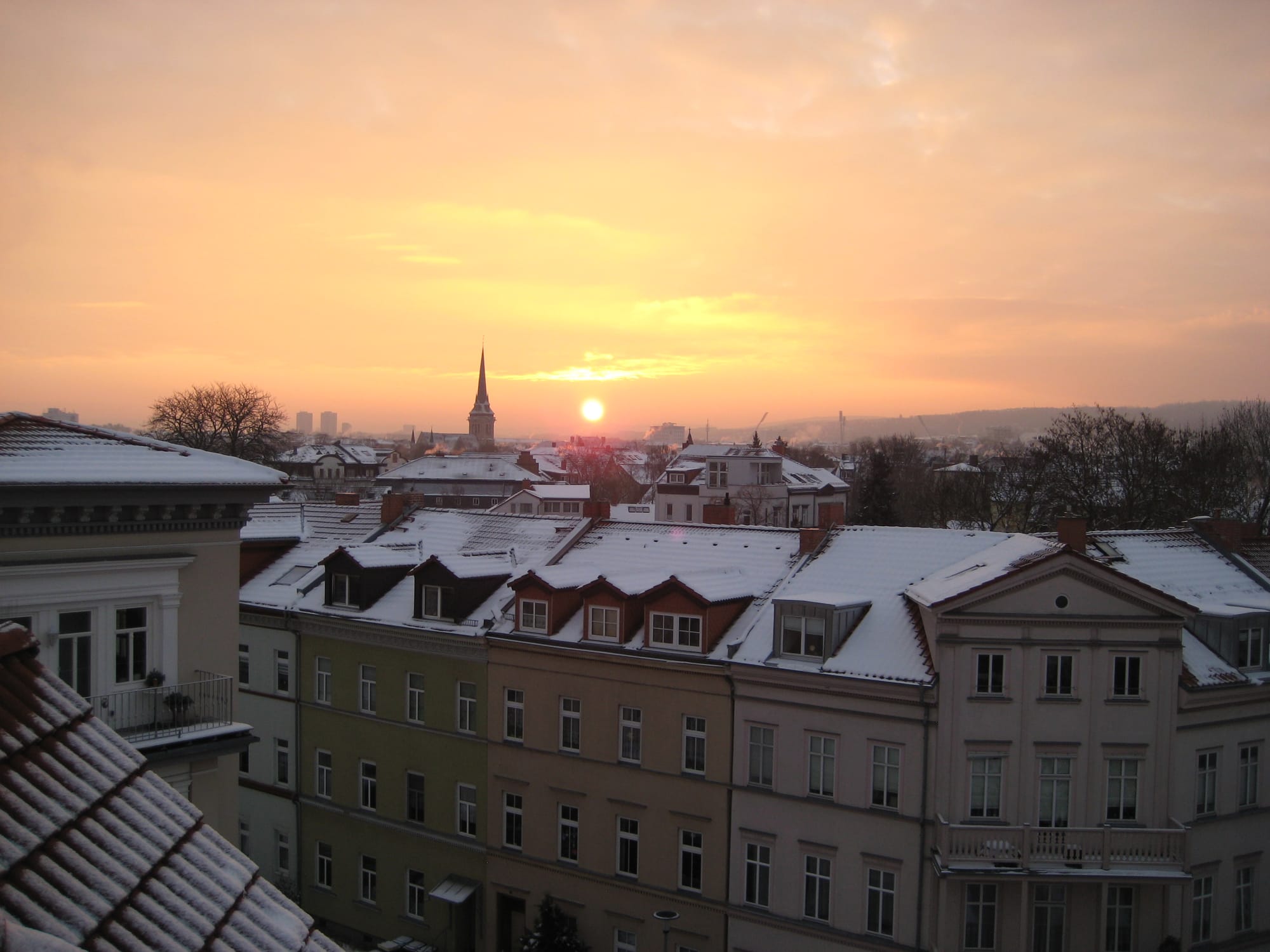 Ein Bild vom Sonnenaufgang. Filterlos. So wie es die alte Ixus kann. Die Sonne steht über der Stadt, gleich neben dem Kirchturm der ihr Hallo sagt.